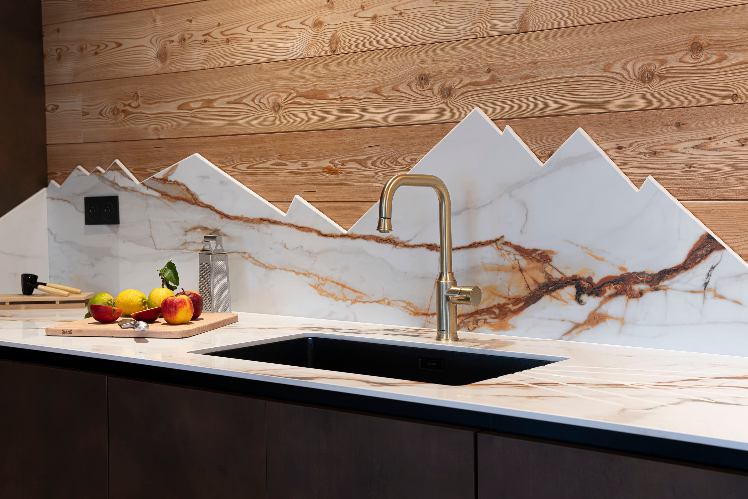 Cuisine avec meubles sombres, crédence en marbre en montagnes et suspension papillons blancs