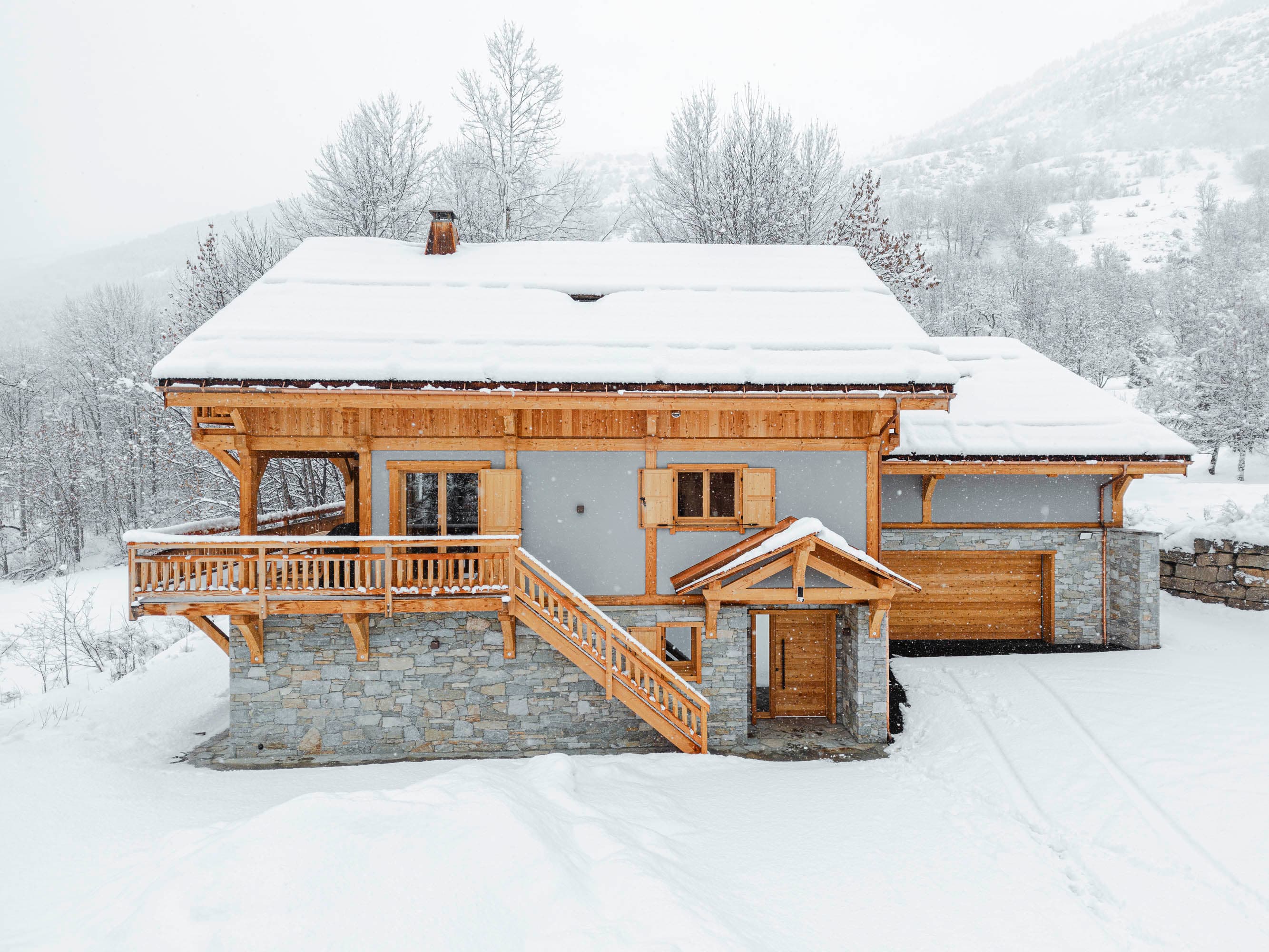 Façade arrière du chalet avec balcons et escalier d'accès enneigé