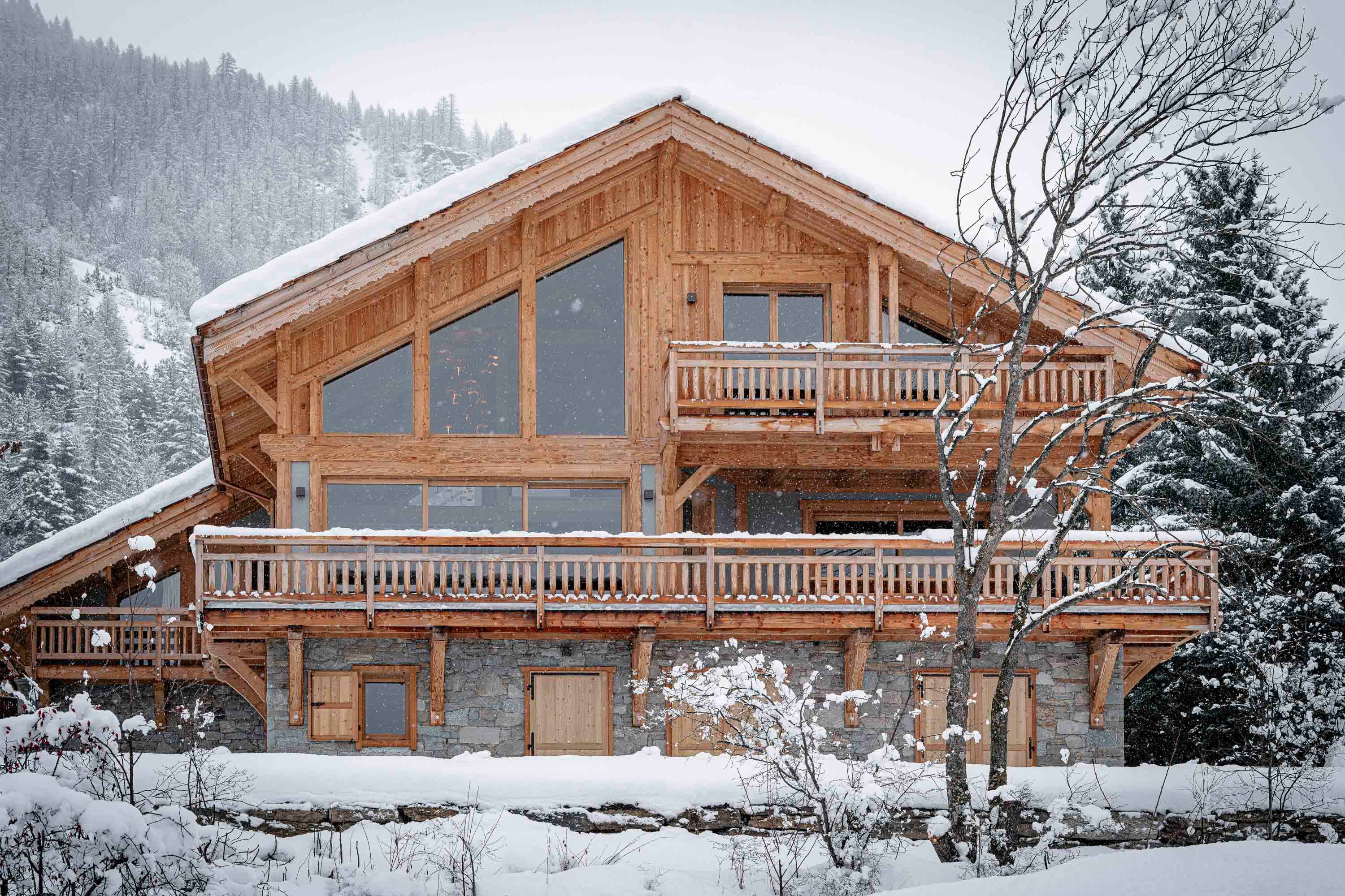 Façade du chalet en bois et pierre sous la neige