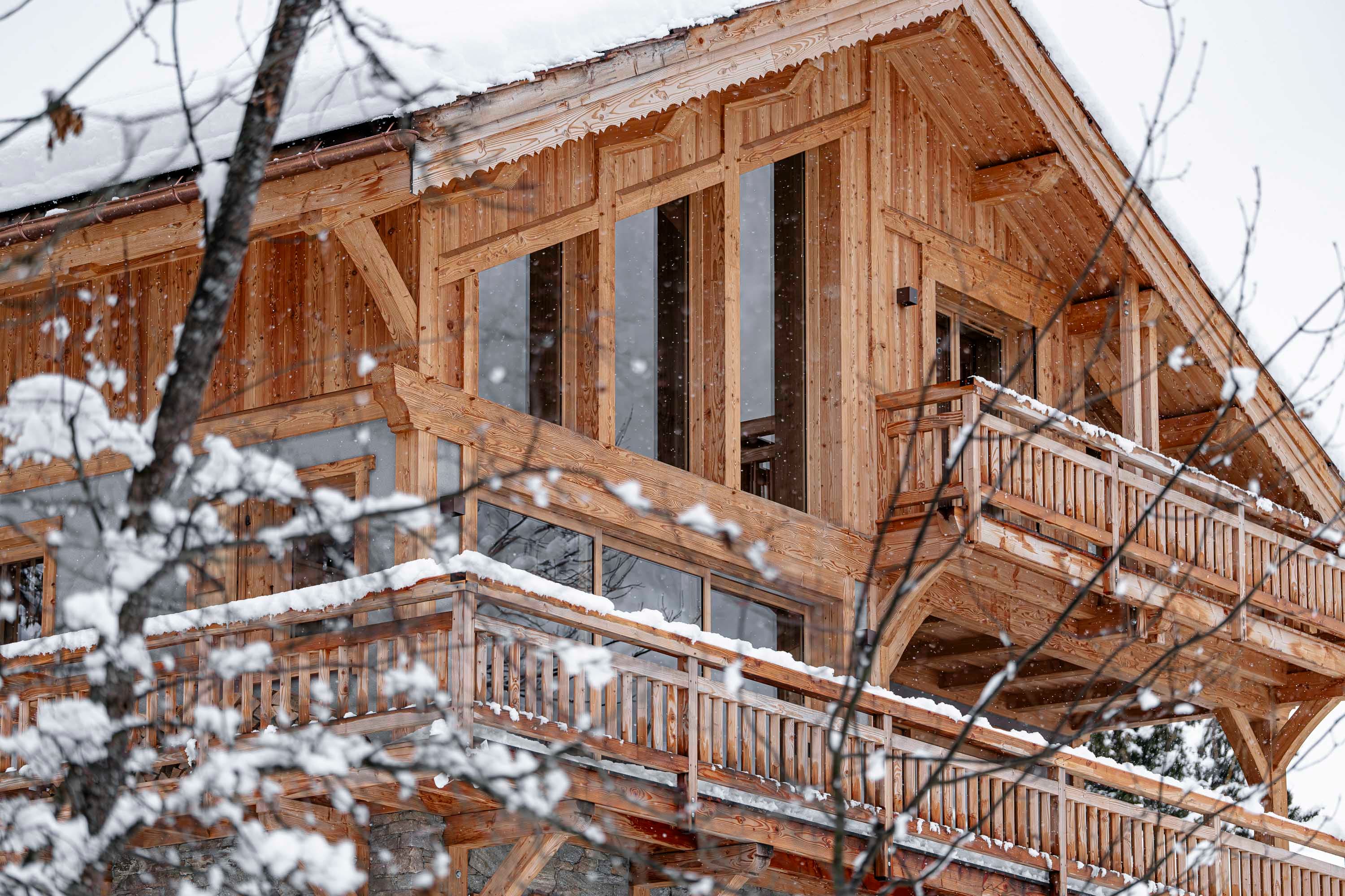 Façade du chalet à travers les arbres enneigés