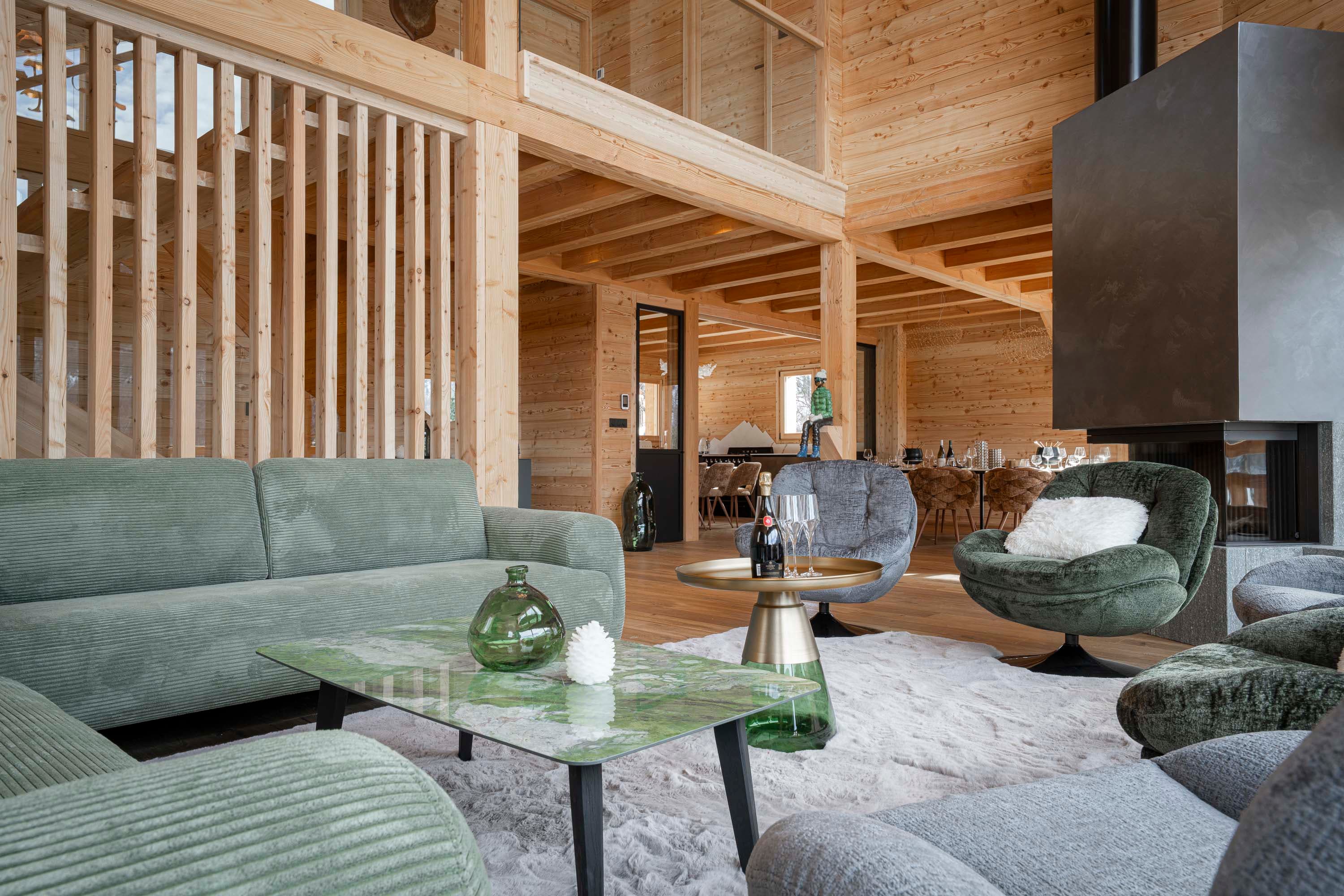Canapé vert, table basse en marbre et cheminée noire avec mezzanine en bois au-dessus