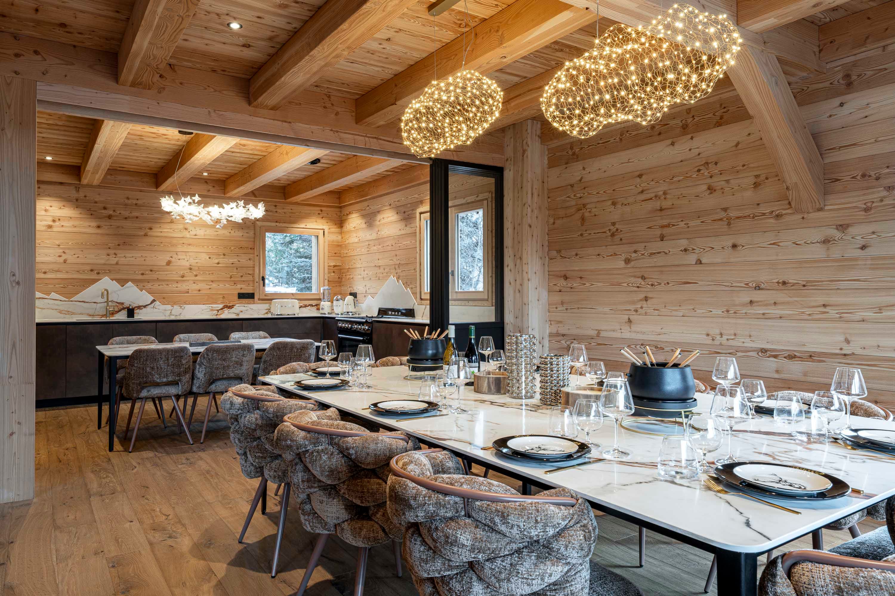 Grande table en marbre Calacatta dressée sous les suspensions nuage avec vue sur les montagnes