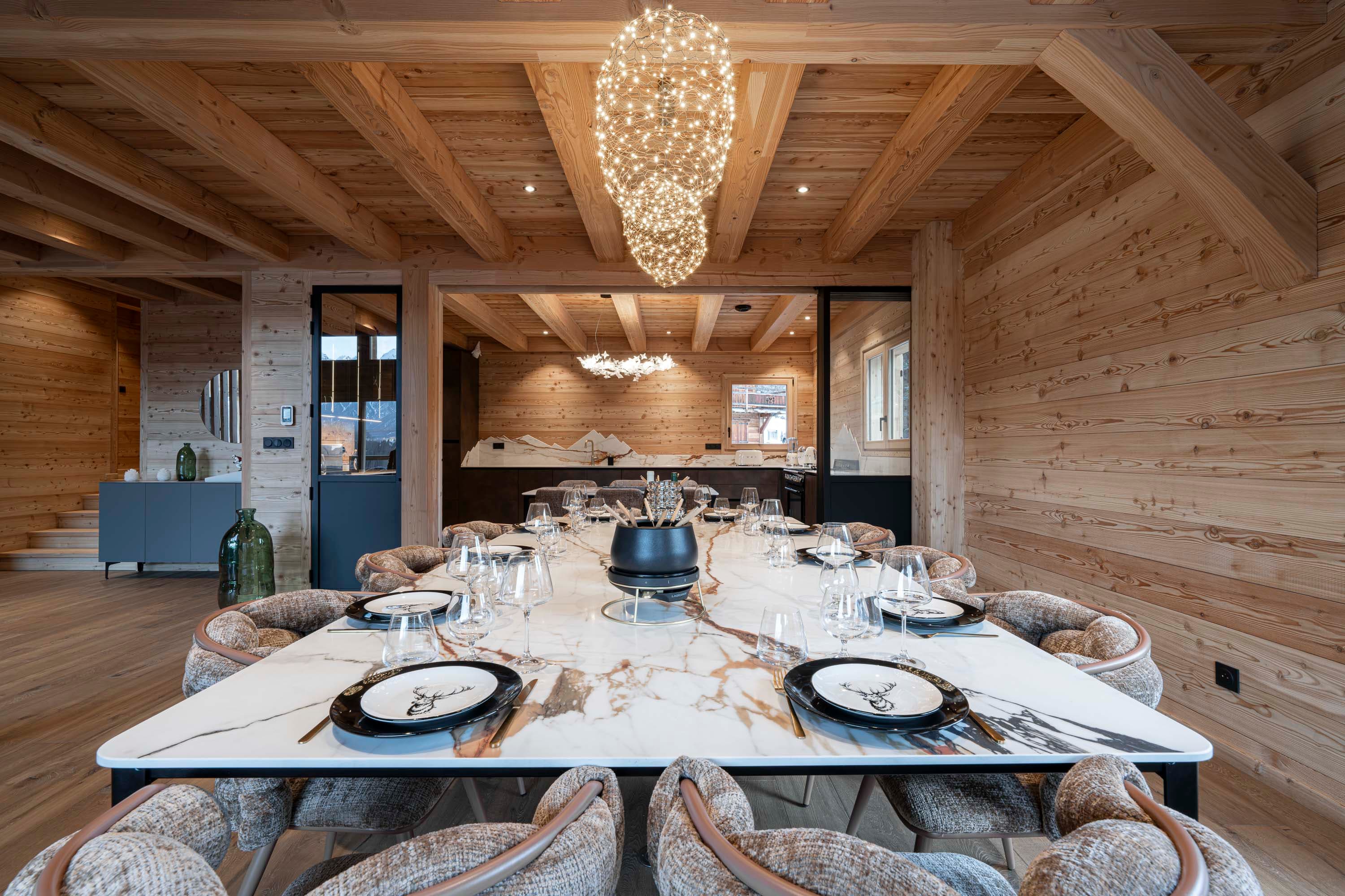 Table en marbre Calacatta dressée avec suspension nuage et vue vers la cuisine en arrière-plan