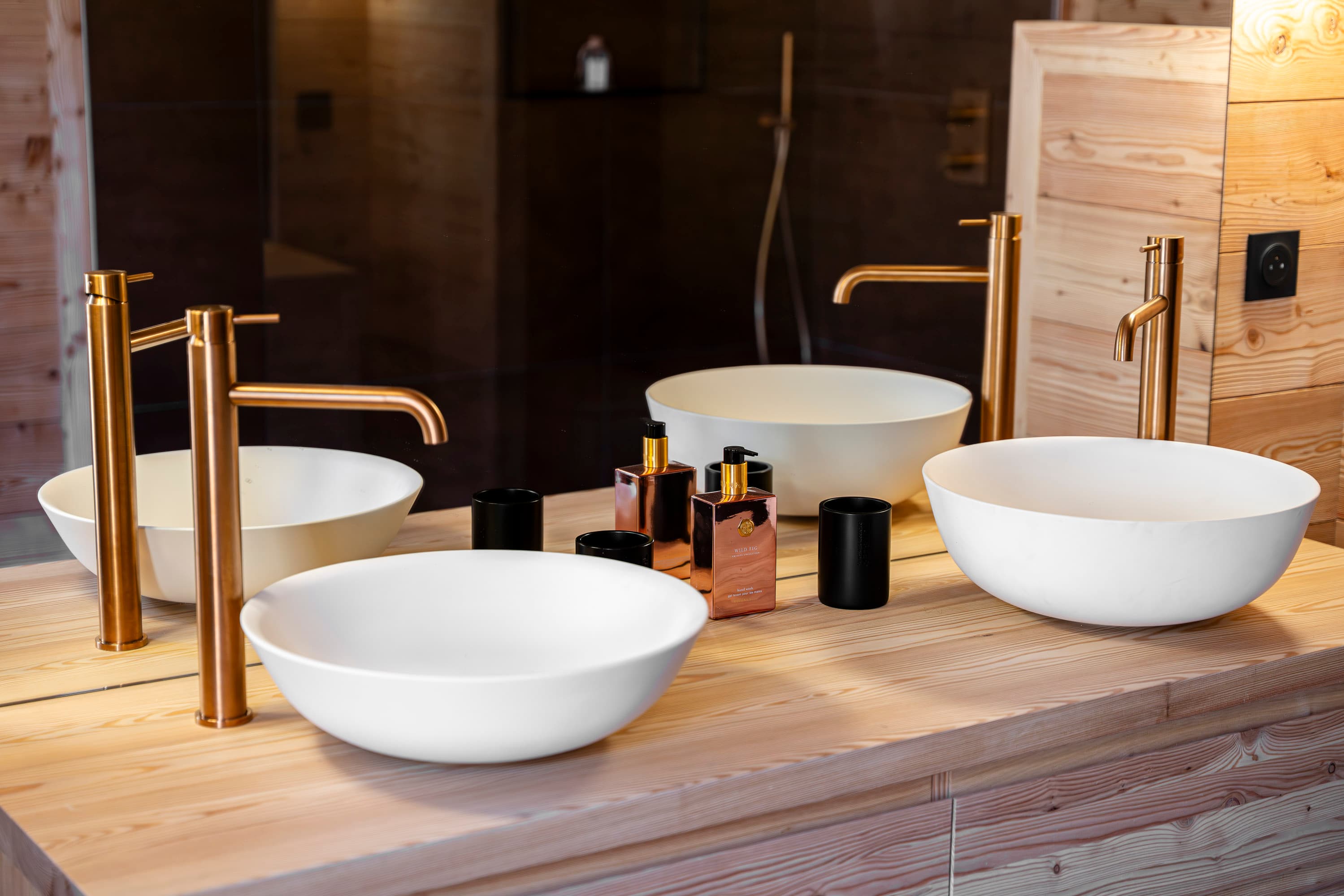 Salle d'eau avec double vasque, robinetterie dorée et produits d'accueil