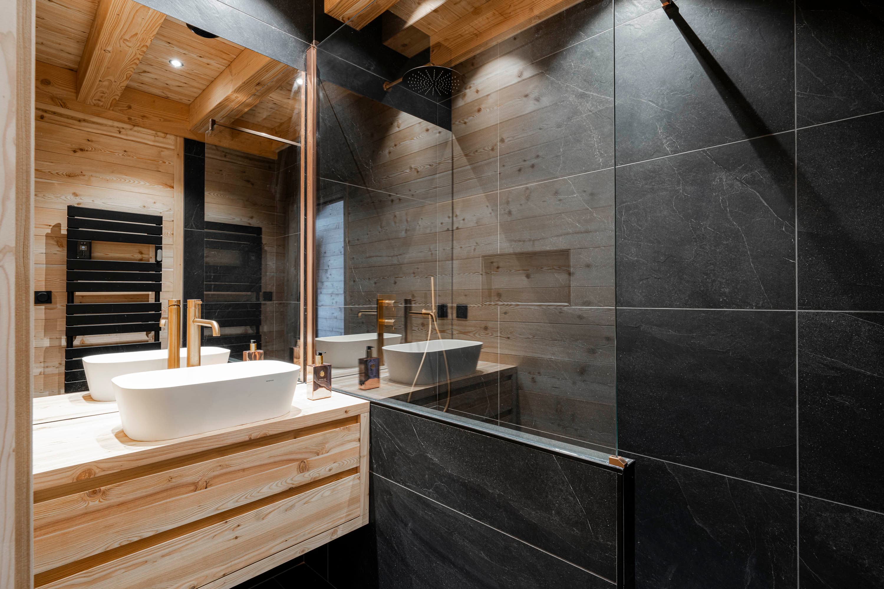 Salle d'eau avec vasque blanche, robinetterie dorée et douche en carrelage ardoise